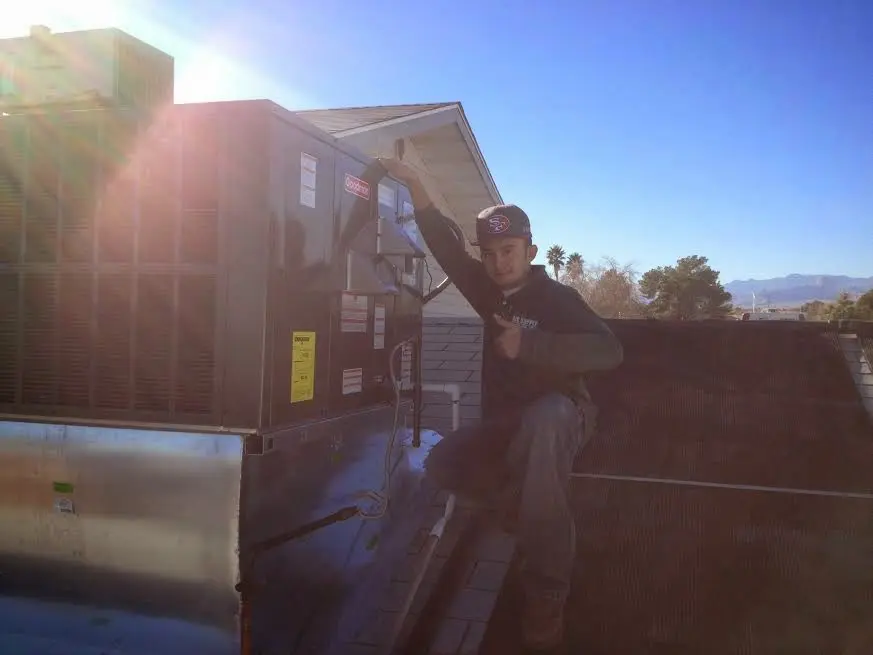 HVAC technician performing AC Tune-Up on a rooftop unit in Benton