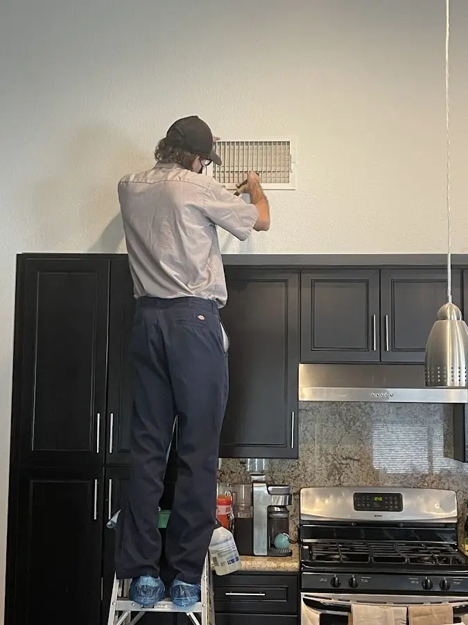 Technician inspecting an air vent during HVAC service in Benton